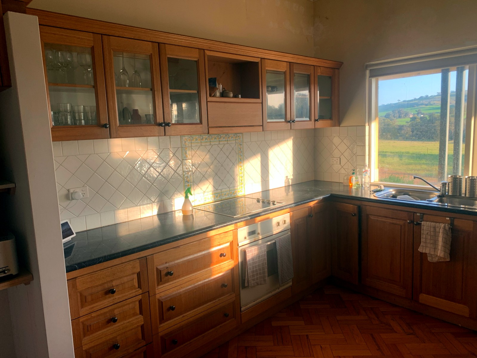 Kitchen before renovation, dated timber cabinetry and tiled splashback